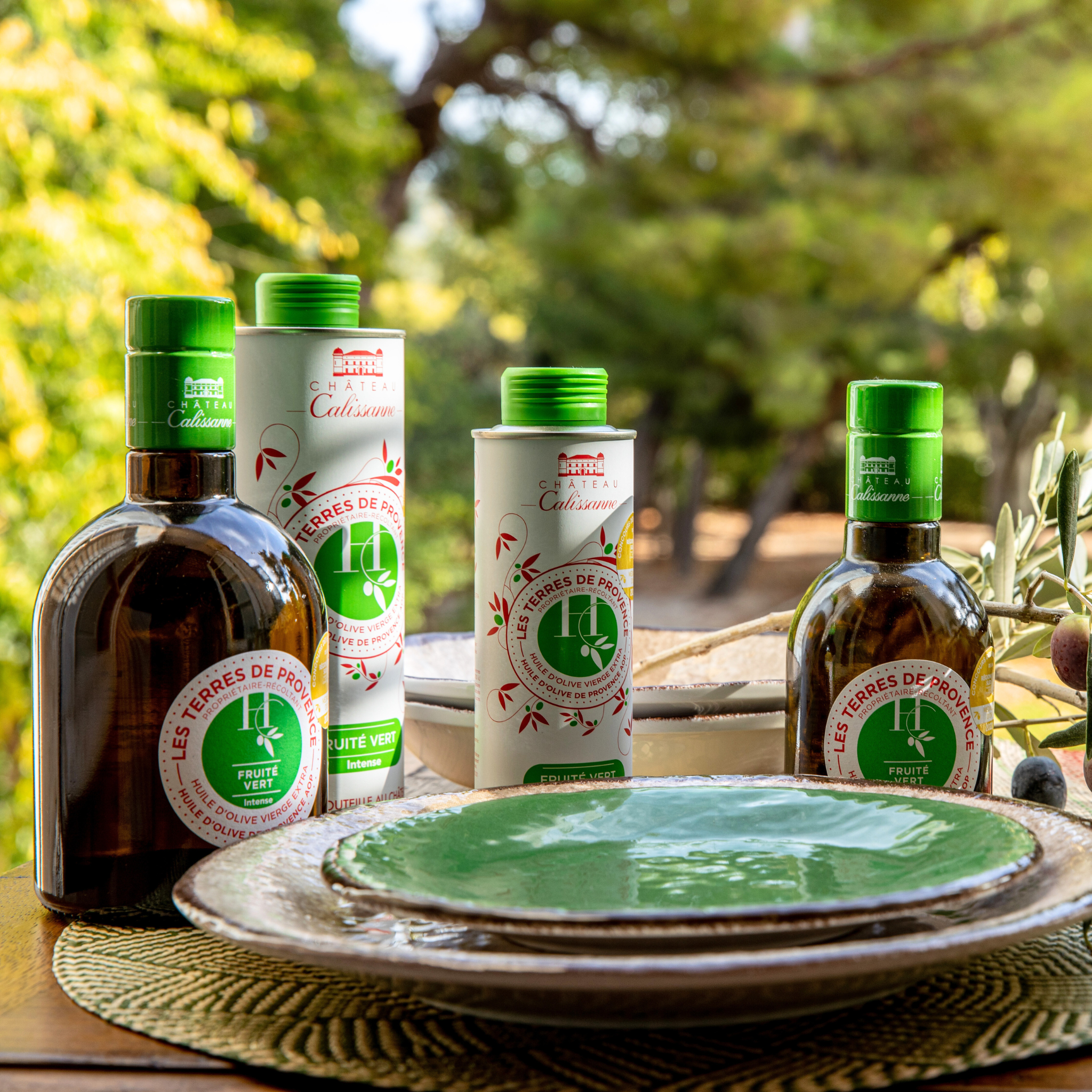 Flaschen und Kanister Olivenöl Les Terres de Provence von Chateau Calissanne auf einem Tisch mit Geschirr