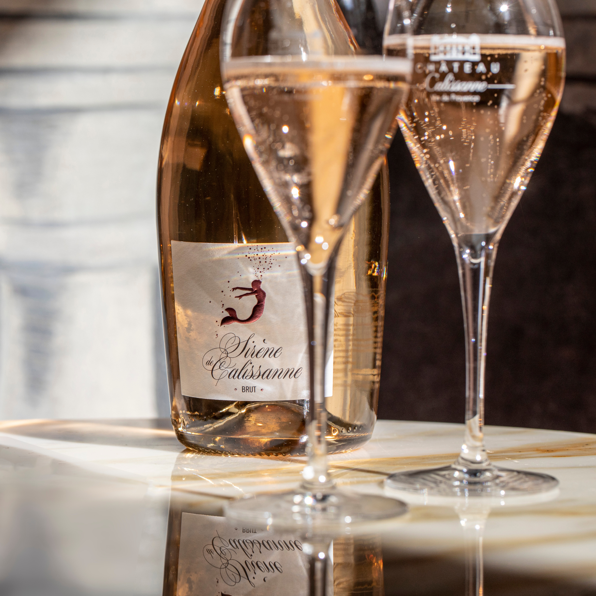 Rosesekt Sirene de Calissanne Flasche auf einem Tisch mit zwei Gläsern 